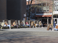 901577 Afbeelding van mensen die genieten van de prille voorjaarszon op de banken bij de zijvleugel van het Stadhuis op ...